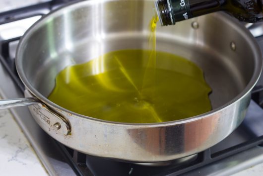 adding olive oil to a wide skillet