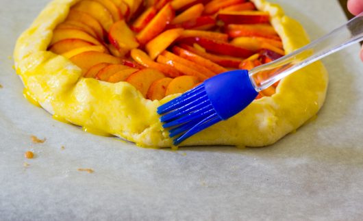 brushing on egg for Rustic Peach Galette