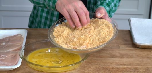 pressing cutlet in pork panko for Crispy Baked Chicken Parmesan