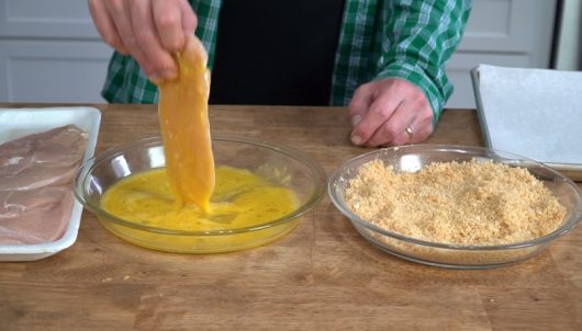 dipping cutlet in egg for Crispy Baked Chicken Parmesan