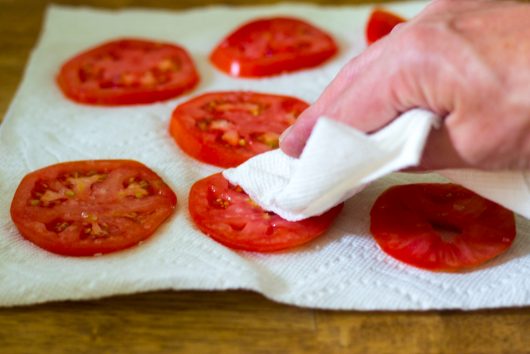 blotting the salted and drained tomatoes for Keto Meatza Pizza