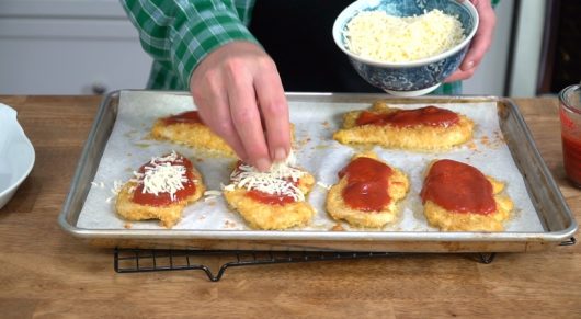top cutlets with shredded mozzarella for Crispy Baked Chicken Parmesan